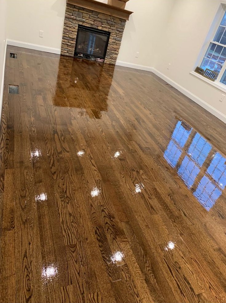 Stained oak floor with a high-gloss finish around a stone fireplace