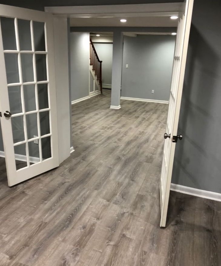 Gray vinyl plank in a finished basement with French doors